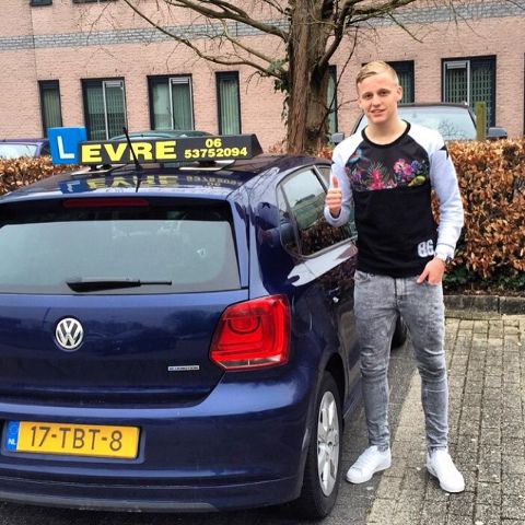 Donny van de Beek in a black t-shirt poses besides a Volkswagen.